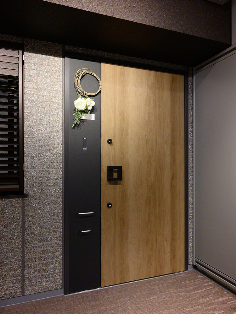 ▲ダークトーンになりがちな共用廊下も木調デザインの玄関ドアで明るい雰囲気に