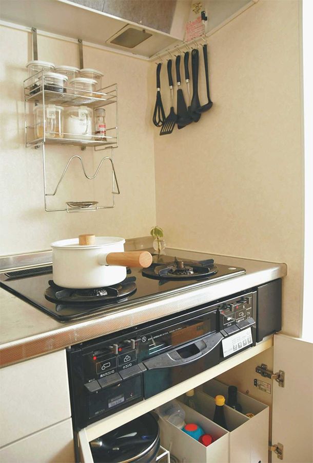 吉川さん宅のコンロ周り。コンロ下にはよく使う鍋や調味料などを収納。使用頻度が高い調理器具などは、吊るす収納にすることで、使い勝手をよくしている。
