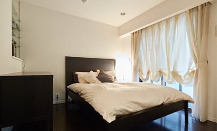 寝室は木製のベッドに合わせて床もフローリングに。カーテンはバルーンシェードタイプを採用。他の空間とは雰囲気を変えて、全体的に柔らかなトーンでまとめている。