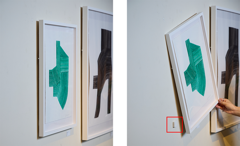 綺麗に垂直に飾られている絵画（左画像）、裏には小さいスチレンボードが貼られている（右画像）。