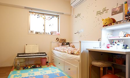 娘さんの部屋の壁はカラフルなウォールステッカーで飾りつけ。家具は白い壁に合わせて選んだ。