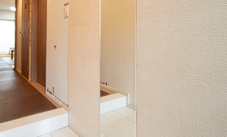 玄関にはオプションサービスで姿見と、脱臭や調湿効果のあるタイルの壁材を設置。