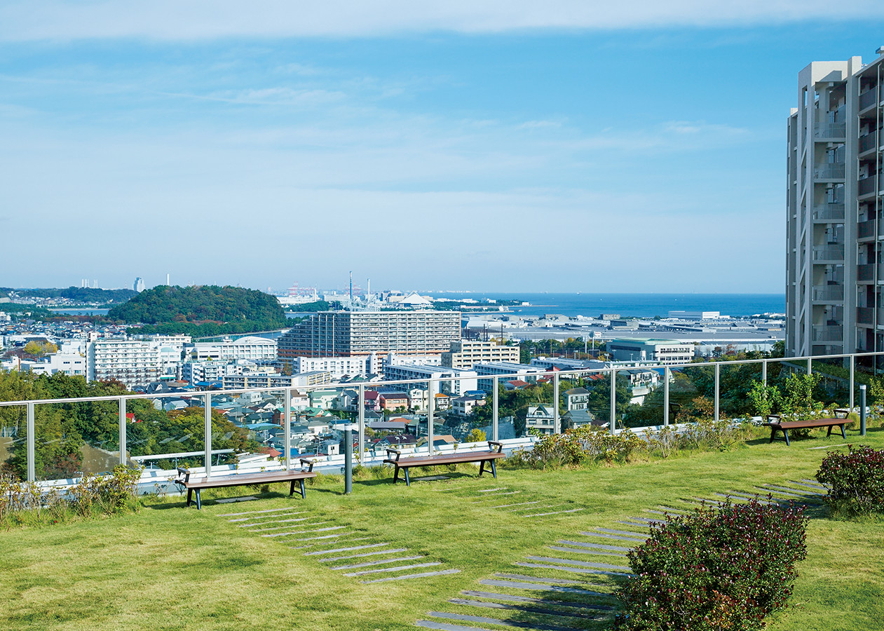 居住者専用の屋上庭園からの眺望。左手に見える小高い緑地は、横浜市金沢区の野島である。