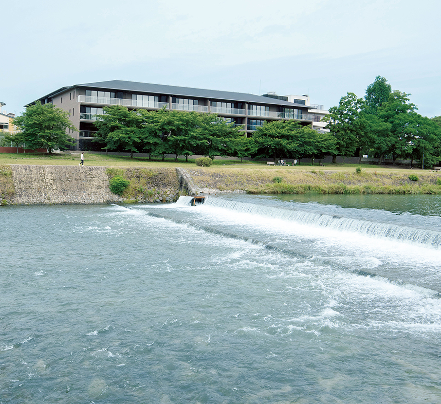 鴨川西岸に建つ『ザ･パークハウス 京都鴨川御所東』を、対岸から眺める。敷地の前にはちょうど堰（せき）があり、川が豊かな表情を見せる。