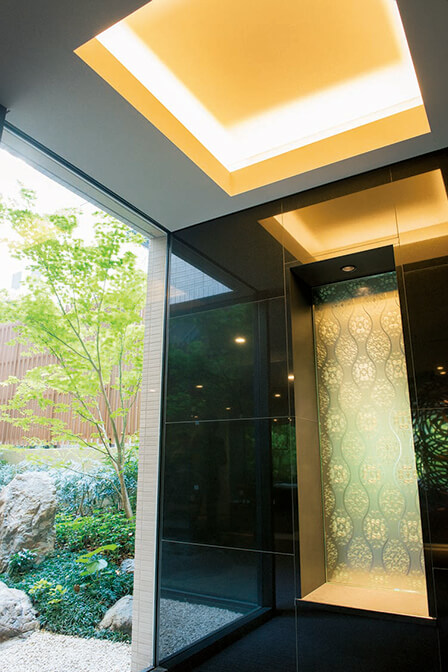 折上げ天井と照明、坪庭と壁面のアートにより上質感を高めたエレベーターホール。