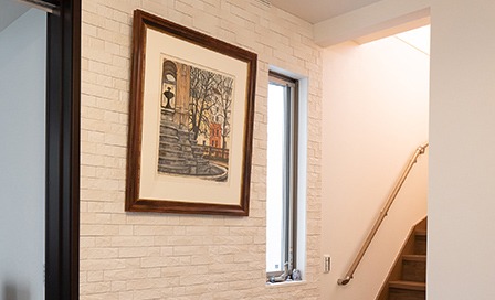 二階へと続く階段脇のスペース。ピクチャーレールを設置して、大好きな絵を飾る。壁面には消臭・調湿効果のあるタイルを貼った。