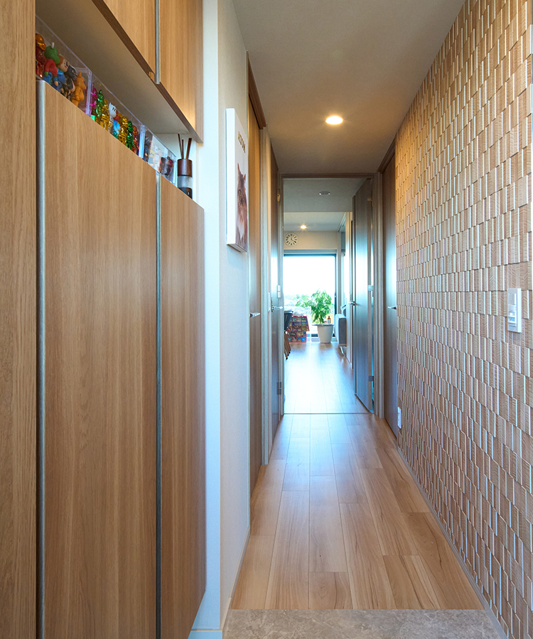 玄関から続く廊下の壁(写真右側)に採用したエコカラット。床や玄関収納の木目調と調和して温かみのある空間。