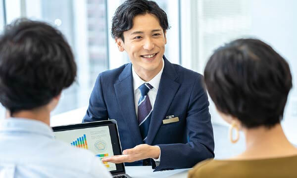 タブレットを使用して夫婦に販売予定価格やスケジュールをご案内している男性